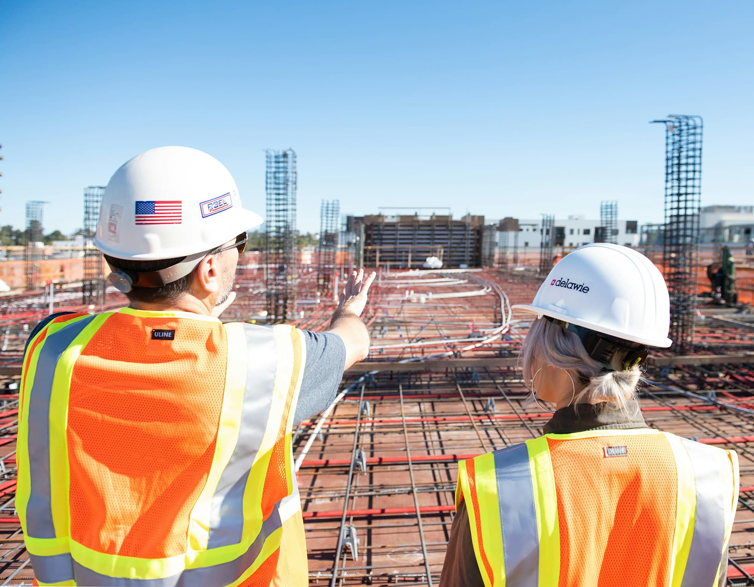 Two site engineers in hard hats reviewing a large site from an elevated position