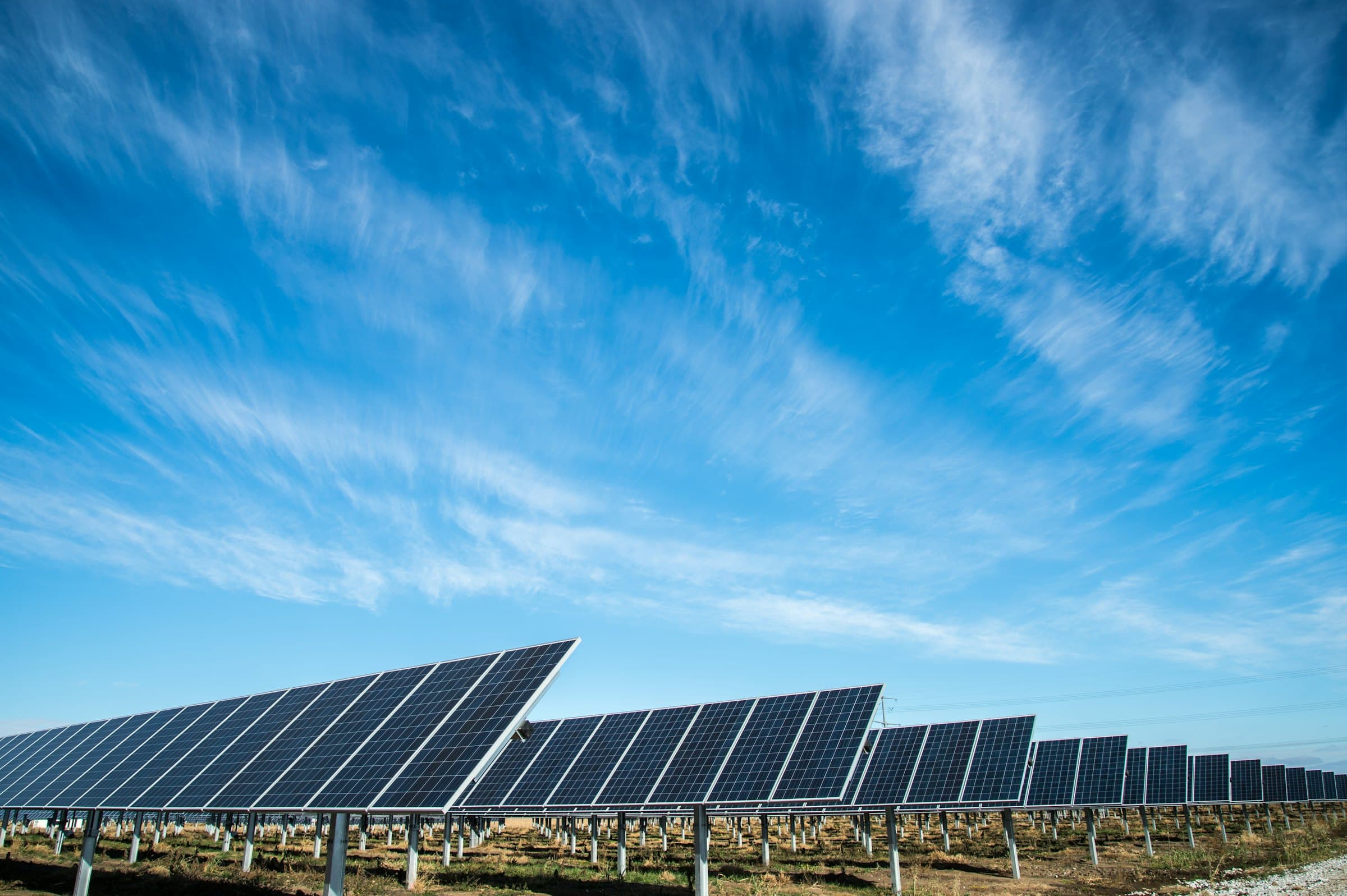 Ground-mounted solar array under a wide blue sky