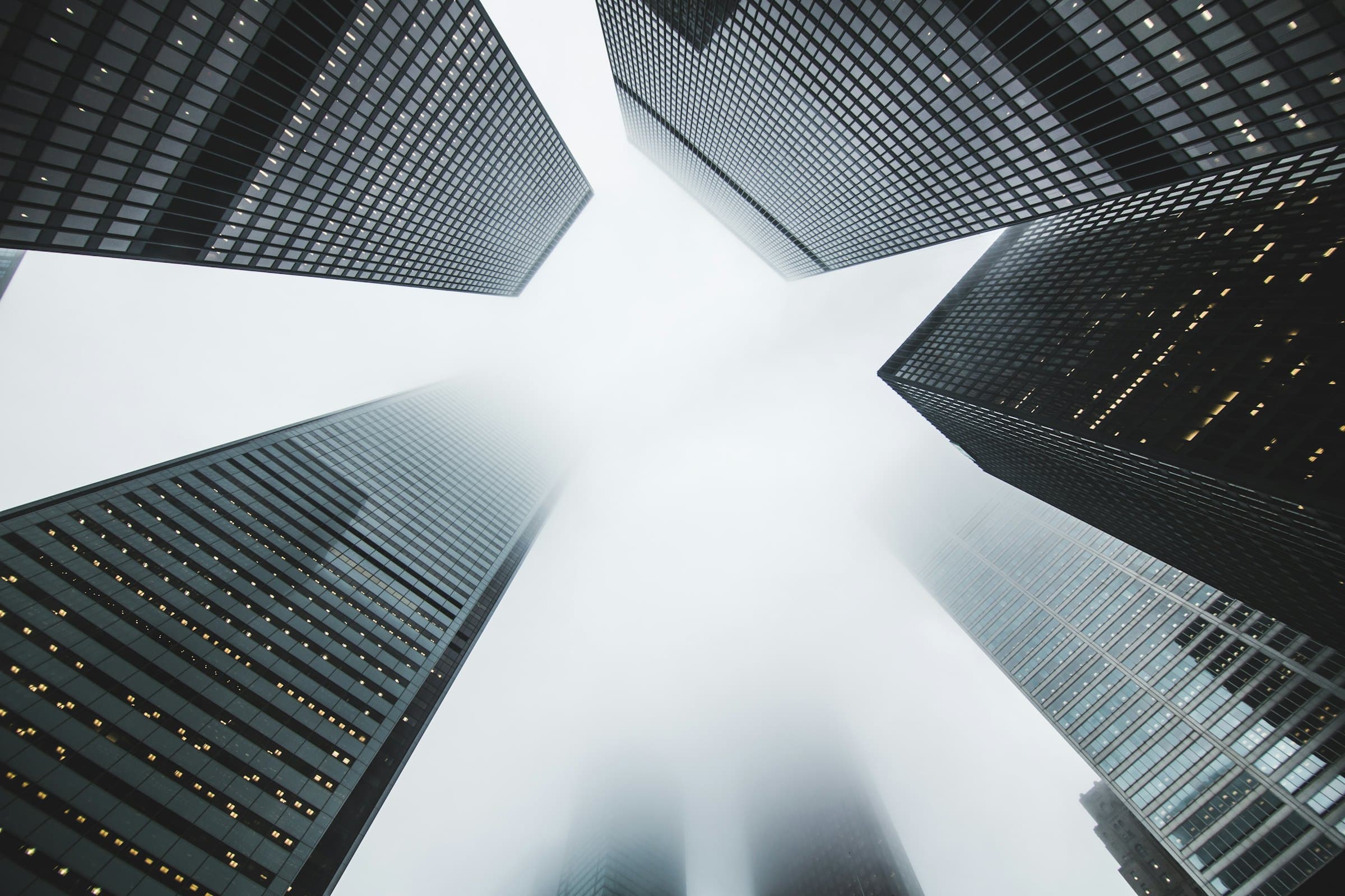 Office towers converging into fog, seen from below